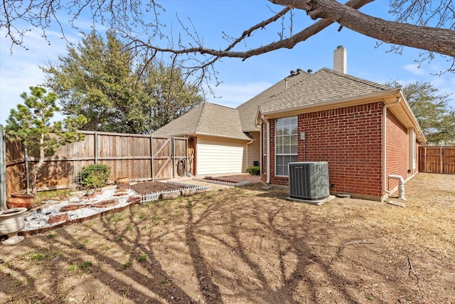 back of house featuring cooling unit, a fenced backyard, a shingled roof, a chimney, and brick siding