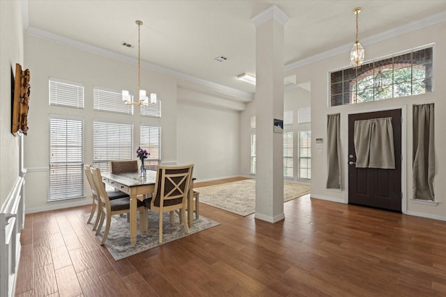 dining space with crown molding, wood finished floors, a wealth of natural light, and a chandelier