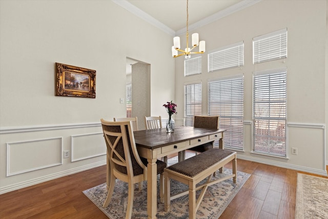 dining space with a notable chandelier, wood finished floors, a wainscoted wall, and ornamental molding