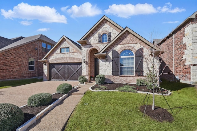 french country style house with a front yard, concrete driveway, a garage, stone siding, and brick siding