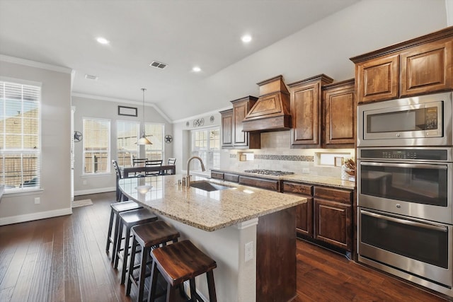 kitchen featuring visible vents, custom exhaust hood, ornamental molding, a sink, and appliances with stainless steel finishes