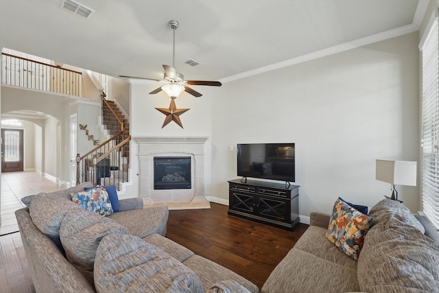 living area with visible vents, arched walkways, wood finished floors, and a tiled fireplace