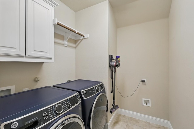 clothes washing area featuring washing machine and clothes dryer, cabinet space, baseboards, and light tile patterned flooring