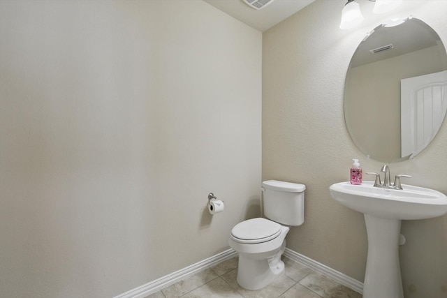 bathroom featuring visible vents, baseboards, toilet, tile patterned floors, and a sink