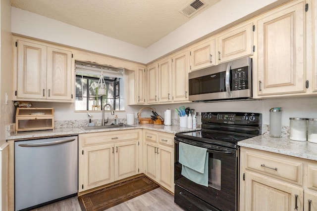 kitchen featuring visible vents, light brown cabinets, stainless steel appliances, and a sink