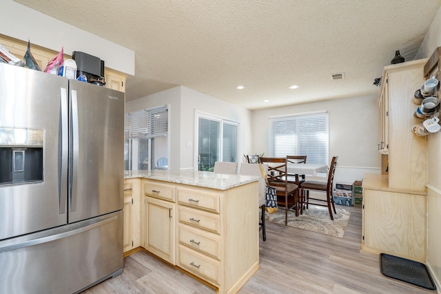 kitchen with light brown cabinets, a peninsula, light wood-style floors, and stainless steel refrigerator with ice dispenser