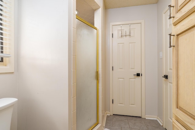 full bath with tile patterned floors, a stall shower, toilet, and baseboards