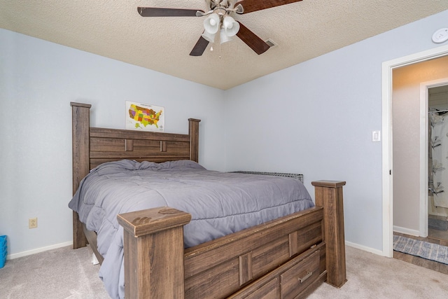 bedroom featuring baseboards, light colored carpet, and a textured ceiling