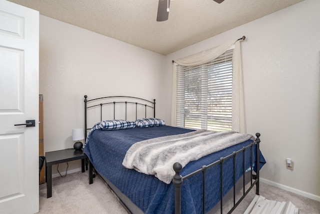 bedroom featuring baseboards, light carpet, a textured ceiling, and ceiling fan