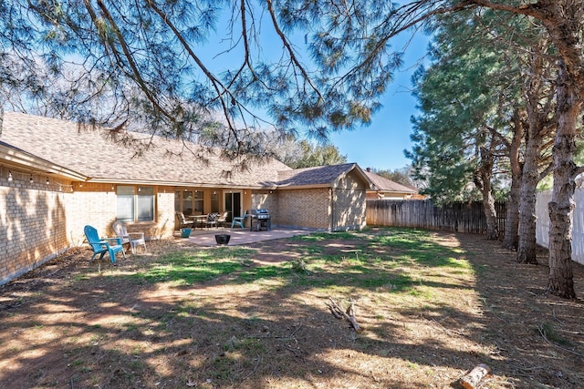 back of house featuring brick siding, roof with shingles, a fenced backyard, and a patio area