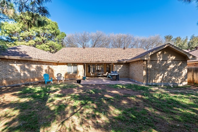 back of house with fence, a yard, a shingled roof, a patio area, and brick siding