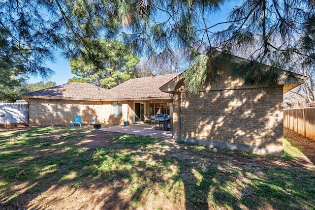 back of property with a patio, a yard, fence, and brick siding