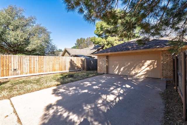 garage with concrete driveway and fence