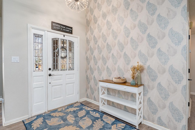 entrance foyer featuring baseboards, a notable chandelier, and wood finished floors