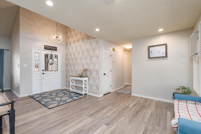 foyer with recessed lighting, baseboards, a textured ceiling, and light wood finished floors