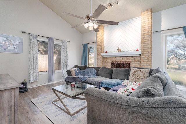 living room featuring a fireplace, a textured ceiling, lofted ceiling, and wood finished floors