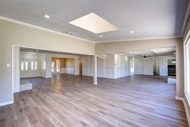 unfurnished living room featuring visible vents, ornamental molding, a decorative wall, wood finished floors, and recessed lighting