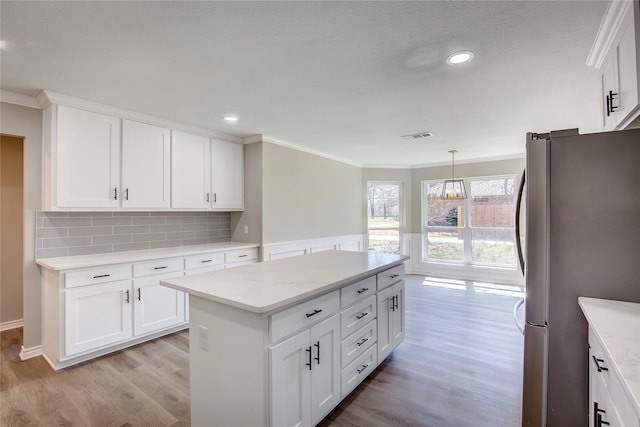 kitchen featuring a kitchen island, backsplash, crown molding, freestanding refrigerator, and light wood-style flooring