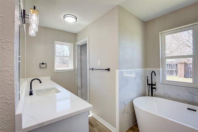 bathroom featuring a walk in shower, a sink, double vanity, wood finished floors, and a soaking tub
