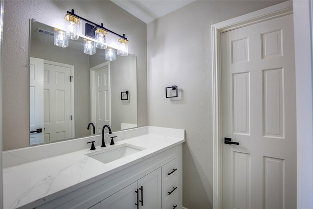 bathroom featuring vanity, a textured wall, and visible vents