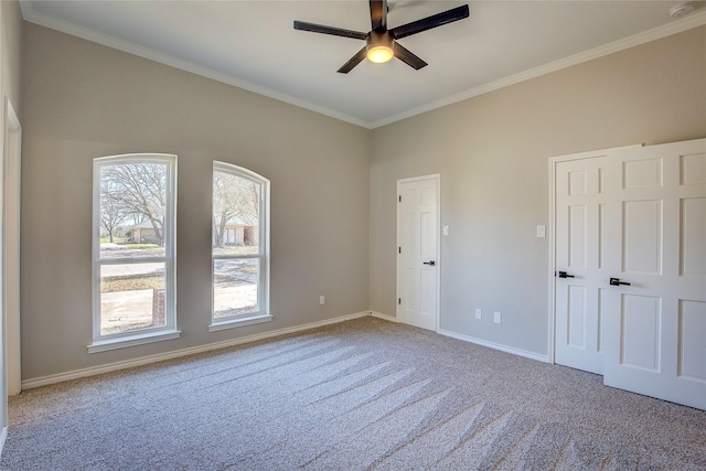 empty room featuring baseboards, carpet flooring, a ceiling fan, and ornamental molding