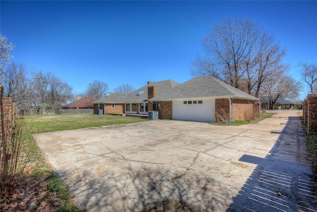 view of front of house with an attached garage, central AC, brick siding, a front yard, and concrete driveway