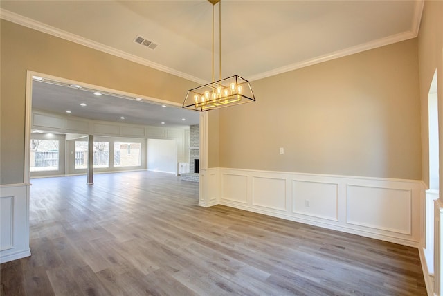 unfurnished dining area with visible vents, ornamental molding, a decorative wall, and an inviting chandelier