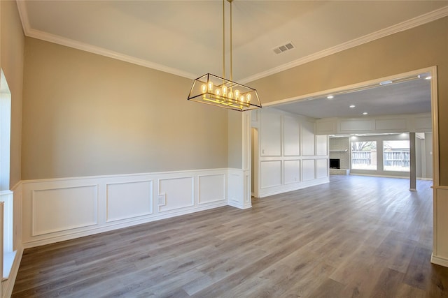 unfurnished dining area with crown molding, a decorative wall, and wood finished floors