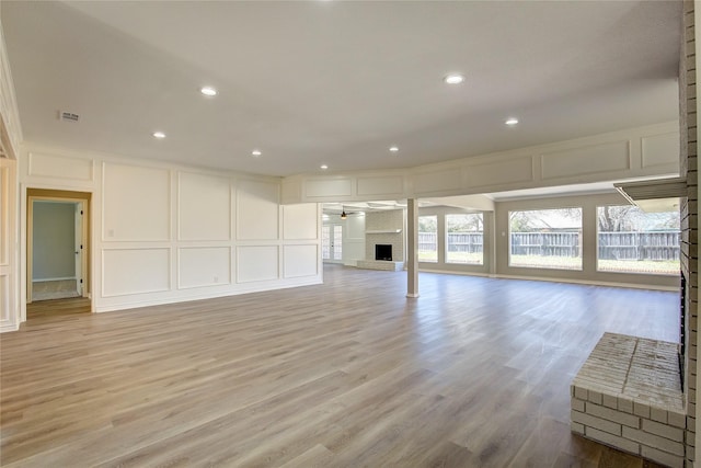 unfurnished living room with visible vents, light wood-style flooring, and a decorative wall