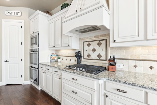 kitchen with white cabinets, appliances with stainless steel finishes, and custom range hood