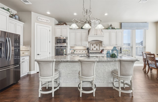 kitchen featuring dark wood-style floors, light stone countertops, visible vents, stainless steel appliances, and decorative backsplash