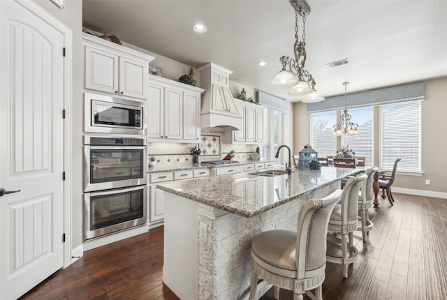 kitchen featuring a sink, tasteful backsplash, dark wood-style floors, stainless steel appliances, and a breakfast bar area