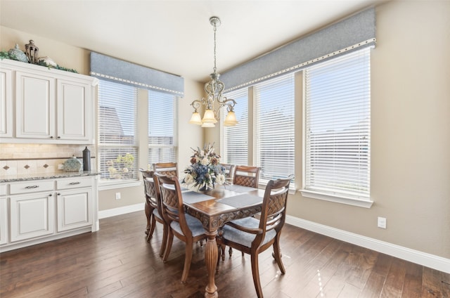 dining area with dark wood-type flooring, a notable chandelier, and baseboards