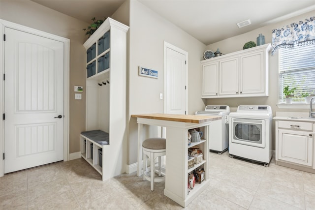 laundry room featuring visible vents, light tile patterned floors, washer and dryer, cabinet space, and a sink