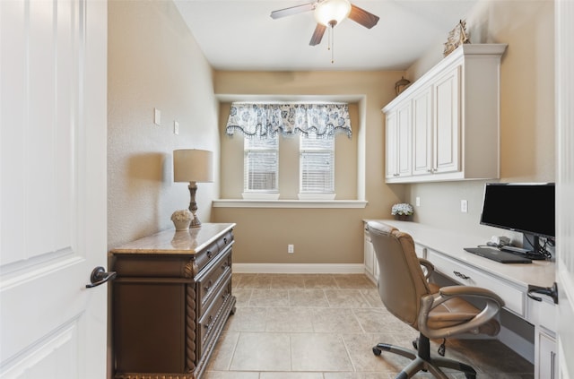 office area with light tile patterned floors, built in desk, a ceiling fan, and baseboards