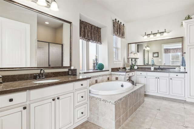 bathroom featuring two vanities, a sink, a shower stall, tile patterned flooring, and a bath