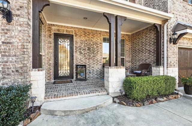 view of exterior entry with brick siding and covered porch