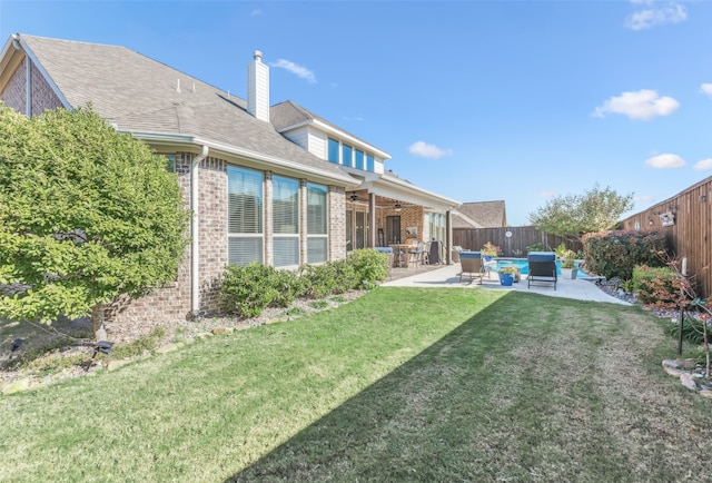 back of house with a patio, brick siding, a fenced backyard, and a lawn