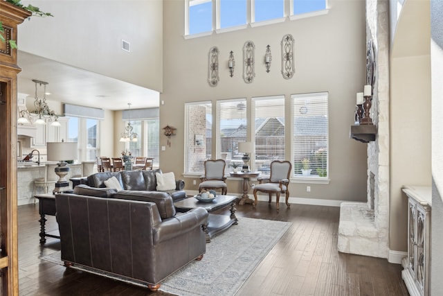 living room with visible vents, baseboards, a high ceiling, an inviting chandelier, and dark wood-style flooring