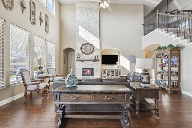 living area with a fireplace, ceiling fan, and dark wood finished floors