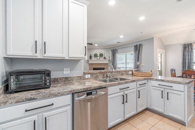 kitchen with a tiled fireplace, a toaster, dishwasher, light tile patterned floors, and a sink