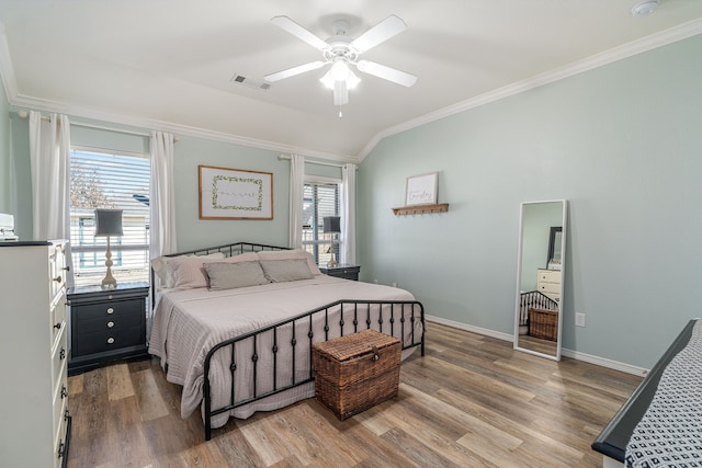 bedroom featuring visible vents, crown molding, baseboards, wood finished floors, and a ceiling fan