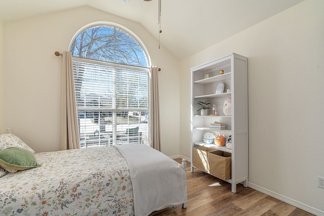 bedroom featuring wood finished floors, baseboards, and vaulted ceiling