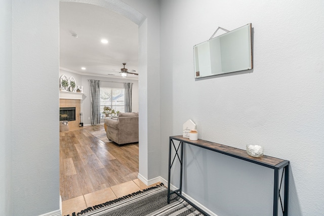 corridor featuring arched walkways, baseboards, and wood finished floors