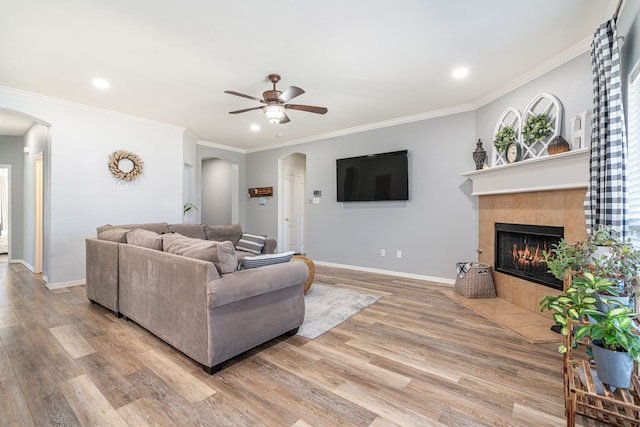 living room with baseboards, arched walkways, wood finished floors, and a tile fireplace