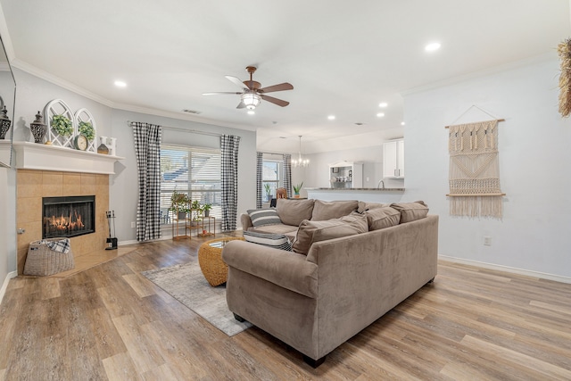 living area with a tile fireplace, recessed lighting, light wood-type flooring, and ornamental molding