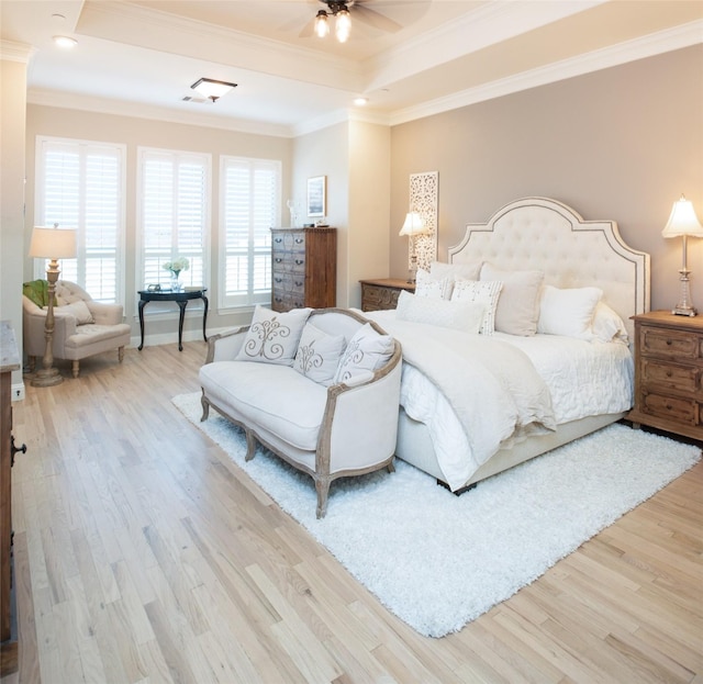 bedroom featuring ornamental molding, a raised ceiling, baseboards, and wood finished floors