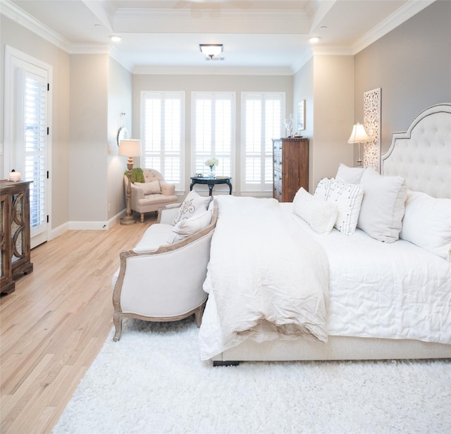 bedroom with light wood-type flooring, a tray ceiling, and ornamental molding