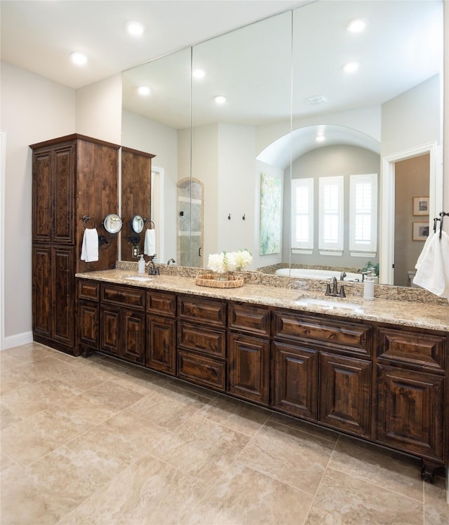 full bathroom with double vanity, recessed lighting, a stall shower, and a sink