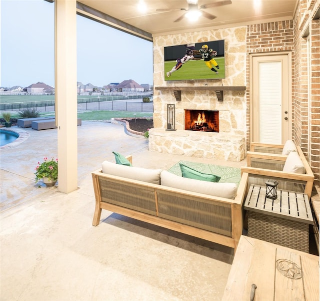 view of patio / terrace with an outdoor living space with a fireplace, a ceiling fan, and fence